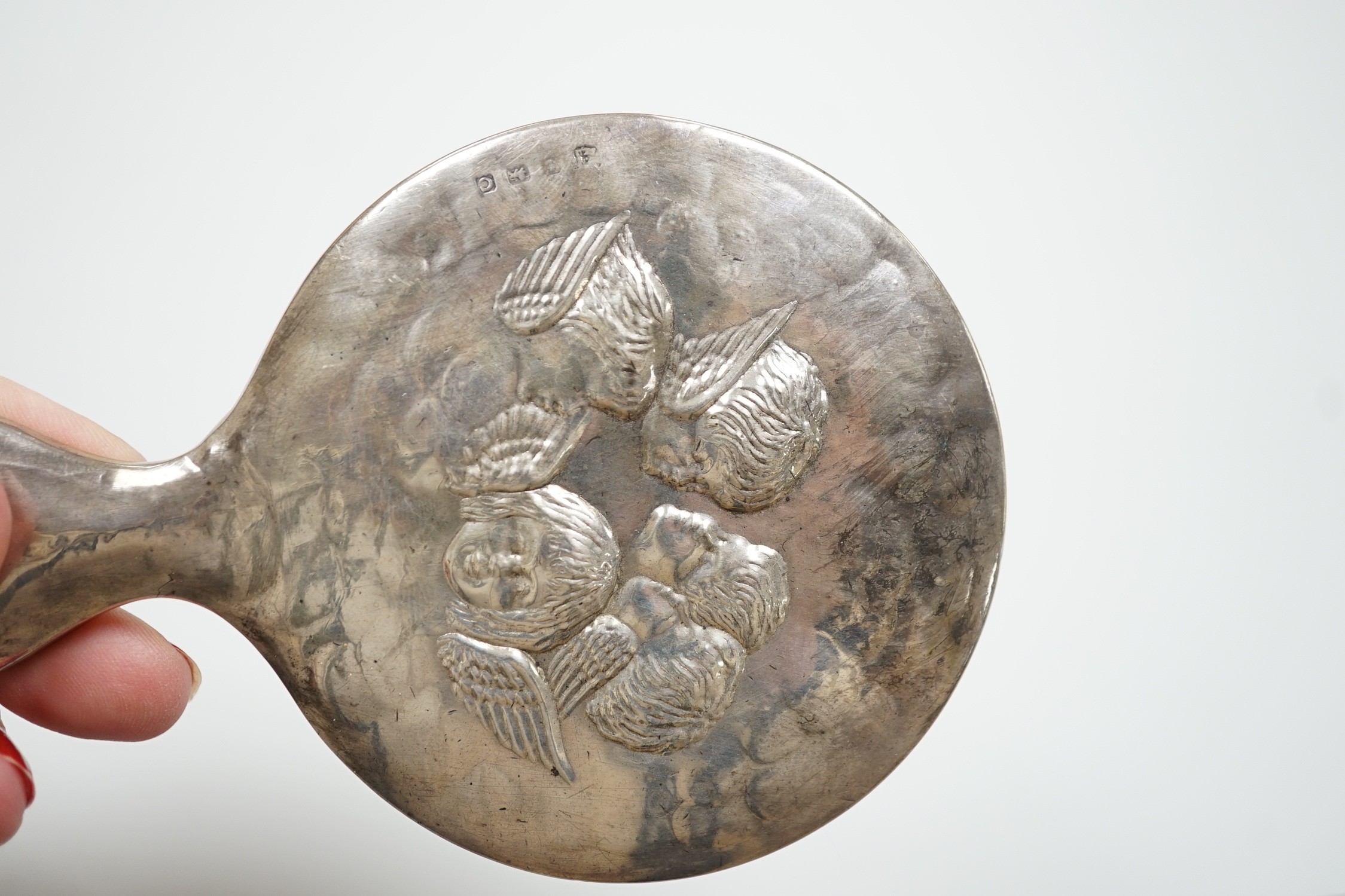 An Edwardian repousse silver Reynolds Angels toilet jar and cover, by William Comyns, London, 1901 and a later similar hand mirror by William Neale Ltd.